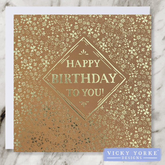 Muted orange and gold foil greetings card with happy birthday to you sentiment, diamond border and gold ditsy floral flower pattern.